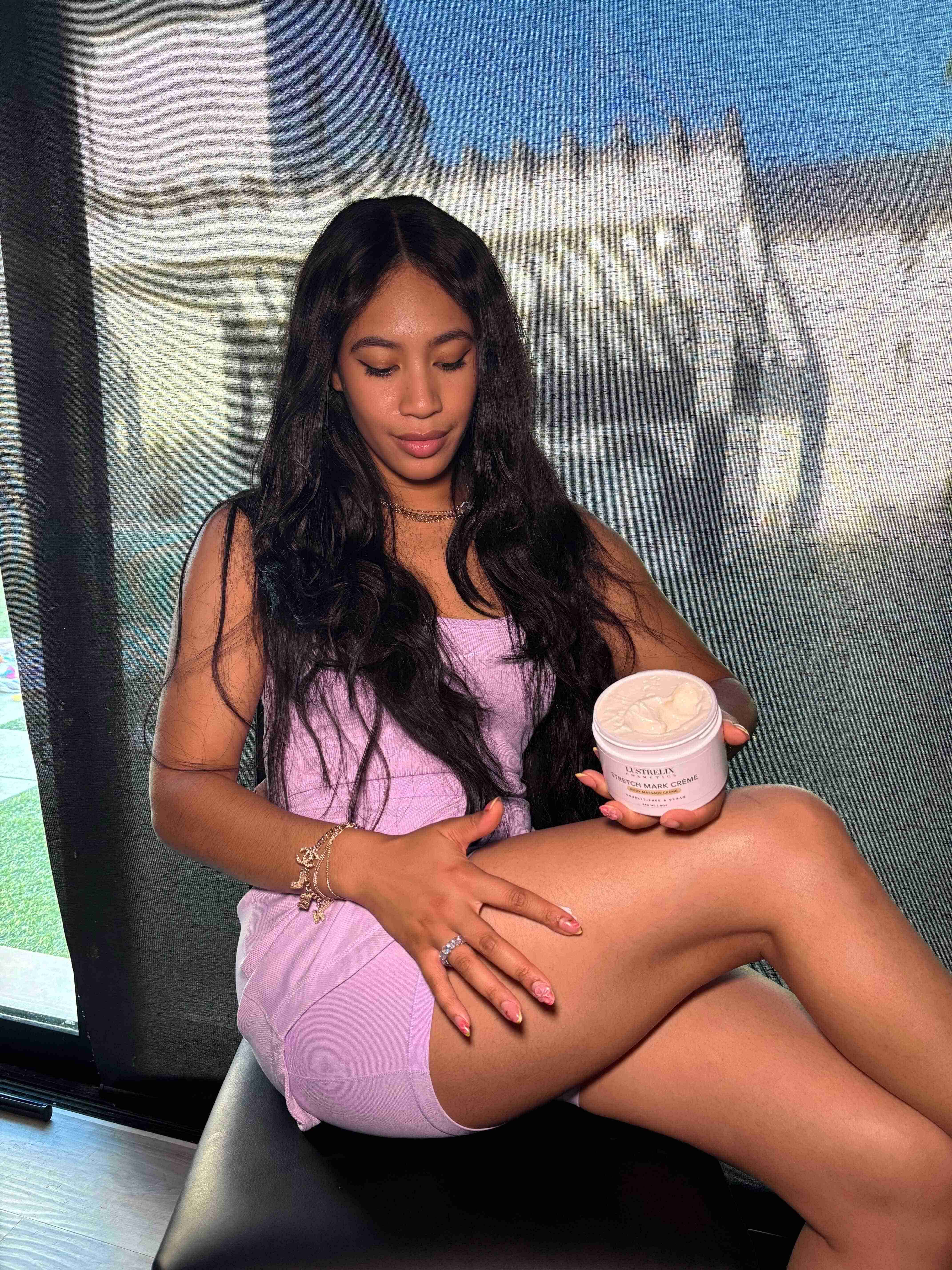 Woman applying cream to her leg in a room with a window in the background